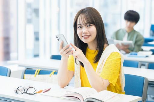 教室でスマホを見る女子大学生 スマホ,笑顔,大学生の写真素材