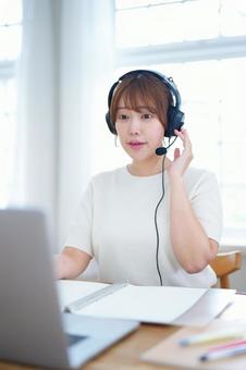 ヘッドセットを押さえ喋っている女性の写真