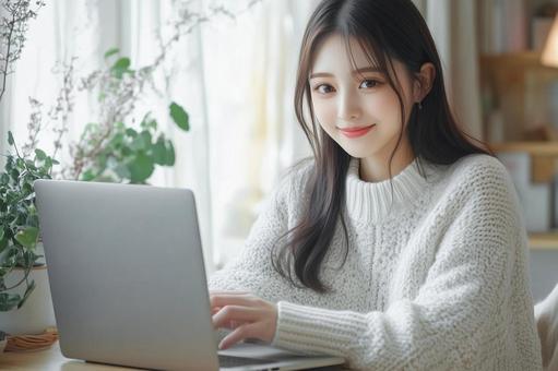 部屋でノートパソコンを操作する若い女性 部屋でノートパソコンを操作する若い女性の写真