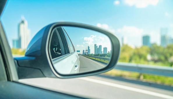 車のサイドミラーに映る道路と街並み 車のサイドミラーに映る道路と街並みの写真