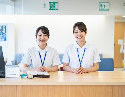 病院の受付コーナーで笑顔で迎える受付嬢 病院の受付コーナーで笑顔で迎える受付嬢の写真
