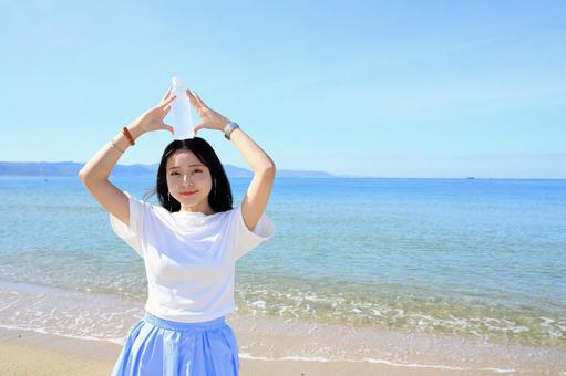 ペットボトルを頭にのせて遊ぶ女性 女性,海,夏の写真素材