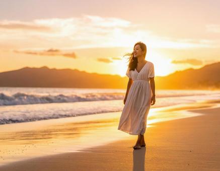 夕日の浜辺を裸足で歩く女性のシルエット 夕日の浜辺を裸足で歩く女性のシルエットの写真