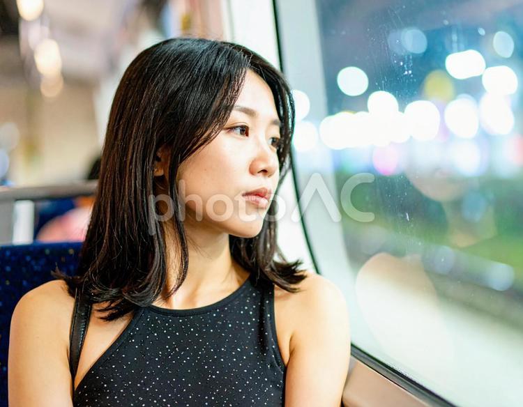 夜の電車で窓の外を見つめる女性 女性,電車,夜の写真素材