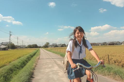 田んぼのあぜ道を自転車で走る女子高生 田んぼのあぜ道を自転車で走る女子高生の写真