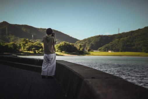 <素材>日暮れの観光地で写真を撮る女性 <素材>日暮れの観光地で写真を撮る女性の写真