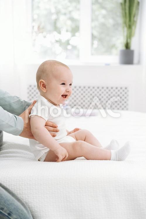 支えてもらいお座りする笑顔の赤ちゃん 赤ちゃん,かわいい,お座りの写真素材