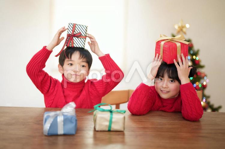 頭にプレゼントをのせて持つ子供たち 男女,クリスマス,プレゼントの写真素材