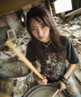 廃工場を背景に力強くドラムを叩く女性 廃工場を背景に力強くドラムを叩く女性の写真