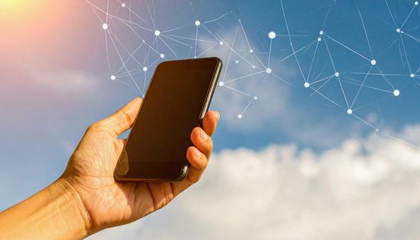 スマートフォンを操作する手 青空背景 スマートフォンを操作する手 青空背景の写真