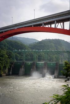 ダム放流と赤い橋の風景 ダム,放流,赤い橋の写真素材