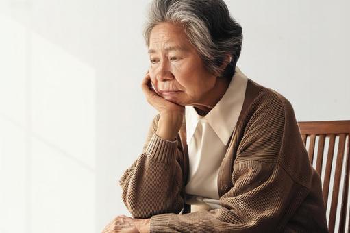 一人で悩み憂鬱な顔の高齢者の女性の写真