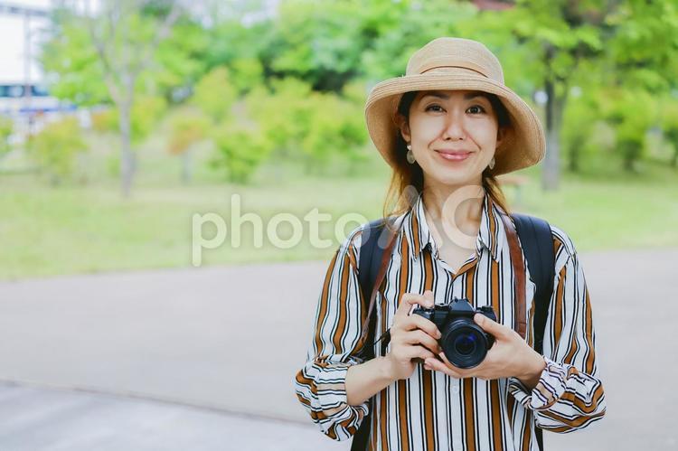 カメラを持って微笑む女性 カメラ,一眼レフ,一眼レフカメラの写真素材