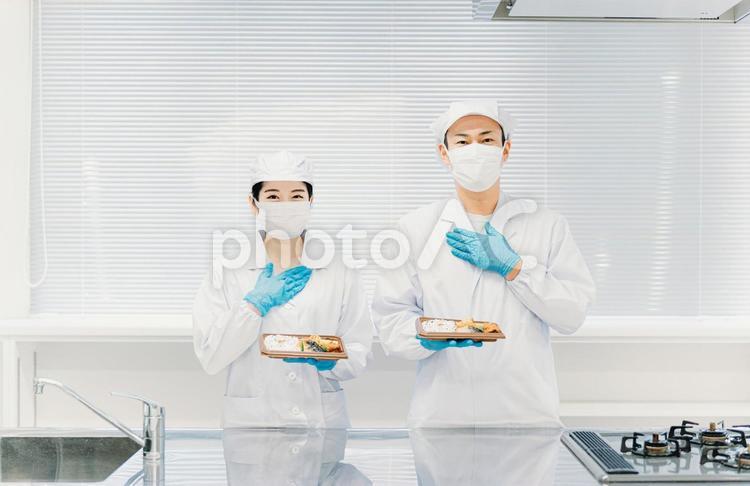 お弁当の盛り付けをする男女（手袋） 食品工場,給食,社員食堂の写真素材