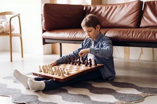 男の子が床に座ってチェスをする 男の子が床に座ってチェスをする チェス,子ども,男の子の写真素材