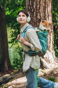 犬を背負って木の横に立つ男性の写真