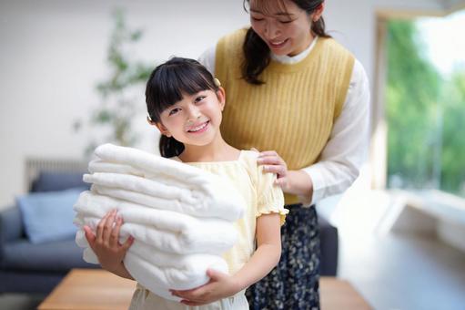 畳んだ洗濯物を持ち笑顔の女の子 畳んだ洗濯物を持ち笑顔の女の子 娘,母,洗濯物の写真素材