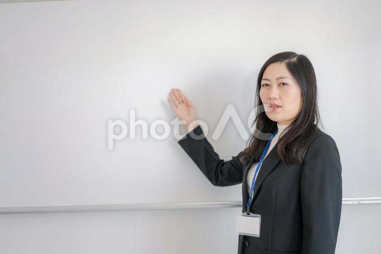 ホワイトボードと案内するビジネス女性 女性,日本人,韓国人の写真素材