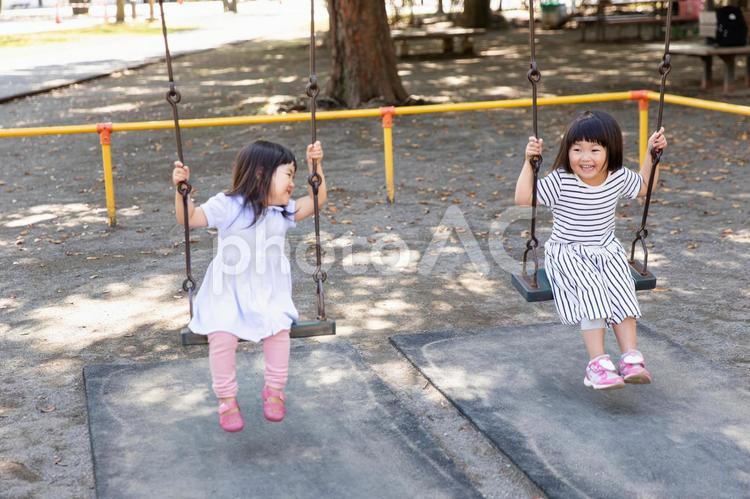 友達とブランコで遊ぶ女の子 ブランコ,ぶらんこ,公園の写真素材
