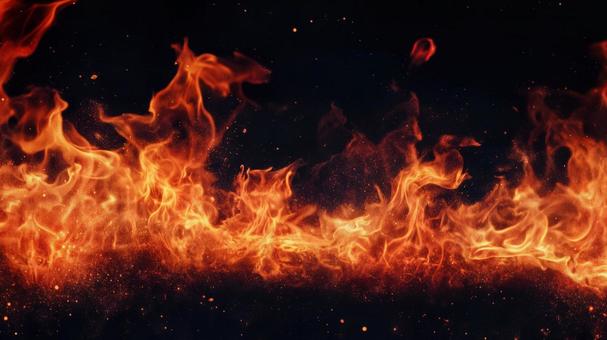 黒背景の地面で燃え上がる炎の写真