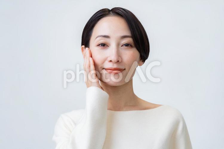 頬に手を当てるカメラ目線の女性 ビューティー,女性,保湿の写真素材