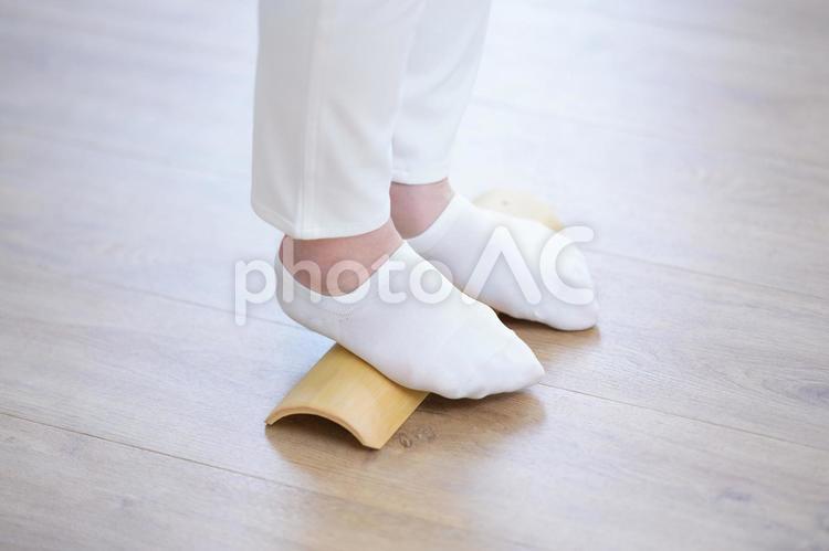 竹の健康器具で足裏を刺激する白い靴下の足元 1人,40代,50代の写真素材