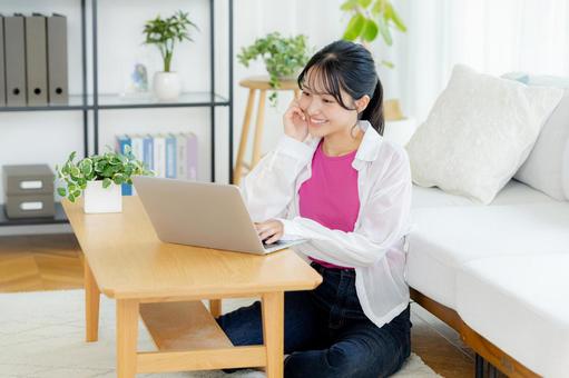 自宅でノートパソコンを操作する若い女性 若い女性,ノートパソコン,笑顔の写真素材
