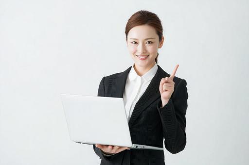 パソコンを持ち指をさす女性-3の写真