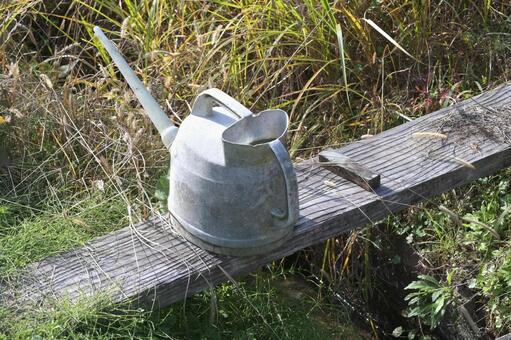 水路脇に放置された古いジョウロと砥石 じょうろ,砥石,雑草の写真素材