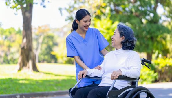 散歩する車椅子の高齢女性と女性介護士 散歩する車椅子の高齢女性と女性介護士の写真