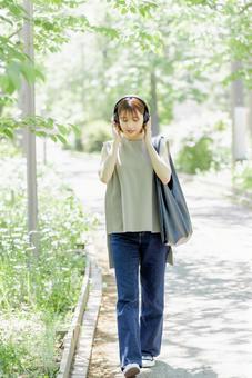 新緑の中ヘッドフォンで音楽を聴く若い女性 新緑の中ヘッドフォンで音楽を聴く若い女性 女性,外出,ヘッドフォンの写真素材