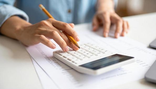 請求する　請求書の上で電卓で計算する女性の写真