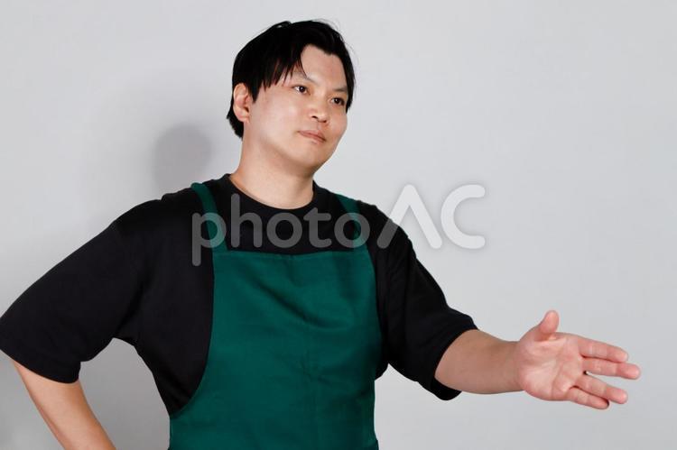 エプロン姿の男性指差し 男性,エプロン,黒い服の写真素材