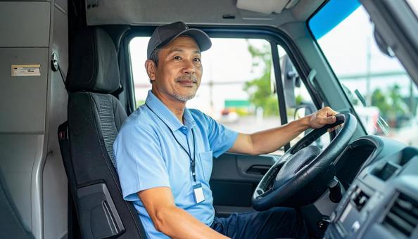 トラックを運転する男性ドライバーの横顔 トラックを運転する男性ドライバーの横顔の写真