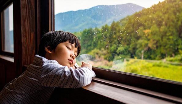 窓際に手をついて眠る男の子 窓際に手をついて眠る男の子の写真