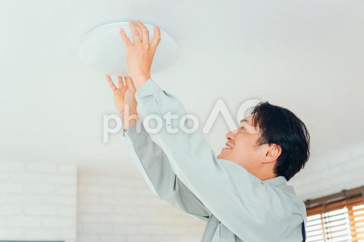 照明器具をチェックする作業着の男性 照明器具,照明,電気工事の写真素材