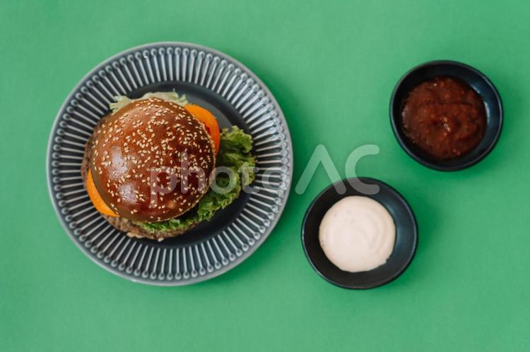 真上から見た緑の背景にある皿に入ったハンバーガー ハンバーガー,パン,食事の写真素材