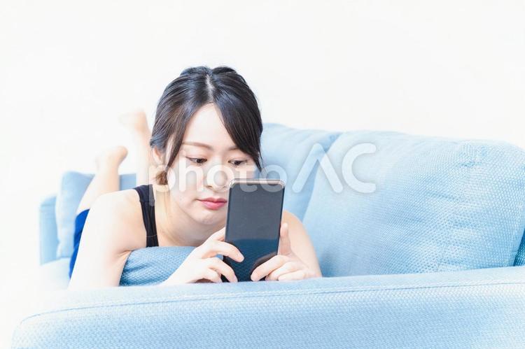 下着を着てスマホを使う若い女性 休日,画面,ネットの写真素材