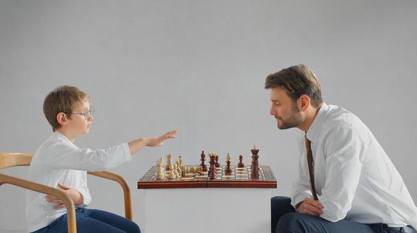向かい合ってチェスをする横向きのお父さんと男の子(グレー背景) 向かい合ってチェスをする横向きのお父さんと男の子(グレー背景) チェス,親子,お父さんの写真素材