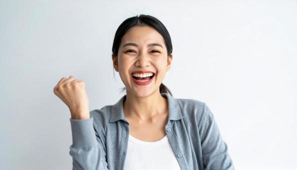 笑顔でガッツポーズする女性のポートレート 笑顔でガッツポーズする女性のポートレートの写真