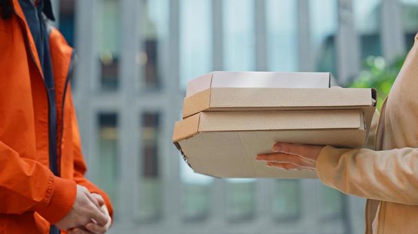 屋外で女性が配達員からピザを受け取る 配達,フードデリバリー,デリバリーの写真素材