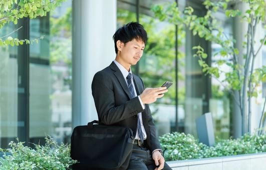 屋外でスマホを使う男性ビジネスマン 屋外でスマホを使う男性ビジネスマン 男性,スマホ,スマートフォンの写真素材