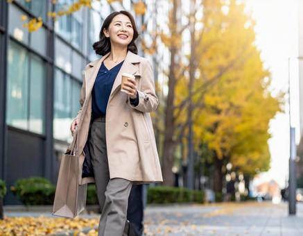 オフィス街を笑顔で歩く通勤中の女性の写真