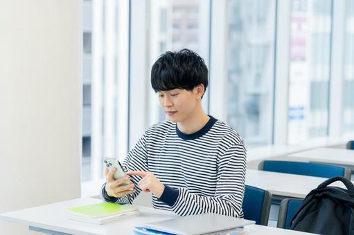 教室でスマホを見る大学生 スマホ,笑顔,大学生の写真素材