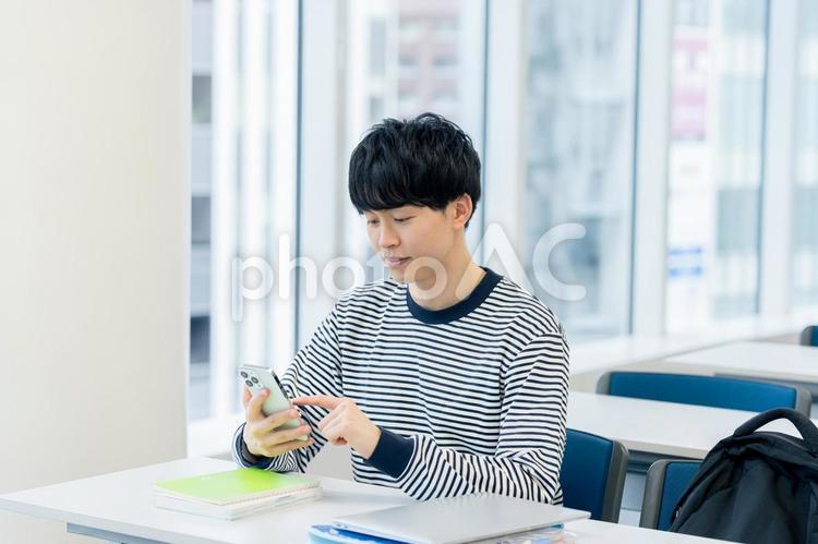 教室でスマホを見る大学生 スマホ,笑顔,大学生の写真素材