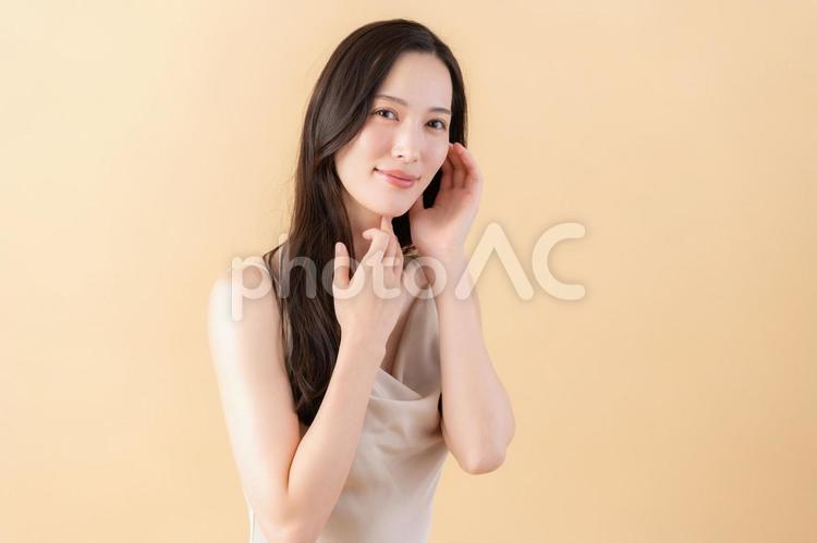 ベージュバックでスキンケアをする若い女性 ビューティー,女性,スキンケアの写真素材