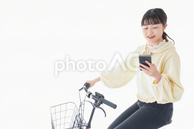 自転車でスマホを使う若い女性 通勤,待ち合わせ,コピースペースの写真素材