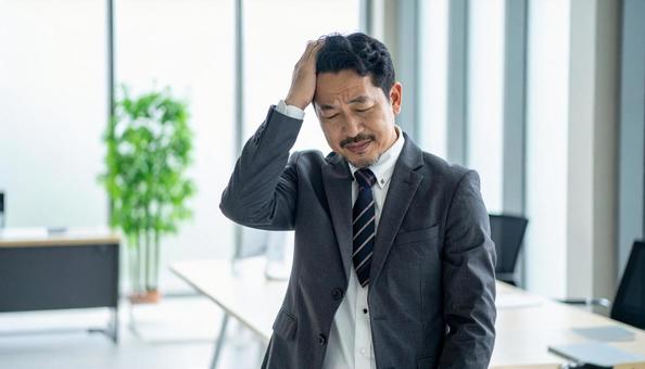 ビジネスイメージ　頭を抱えるビジネスマンの写真
