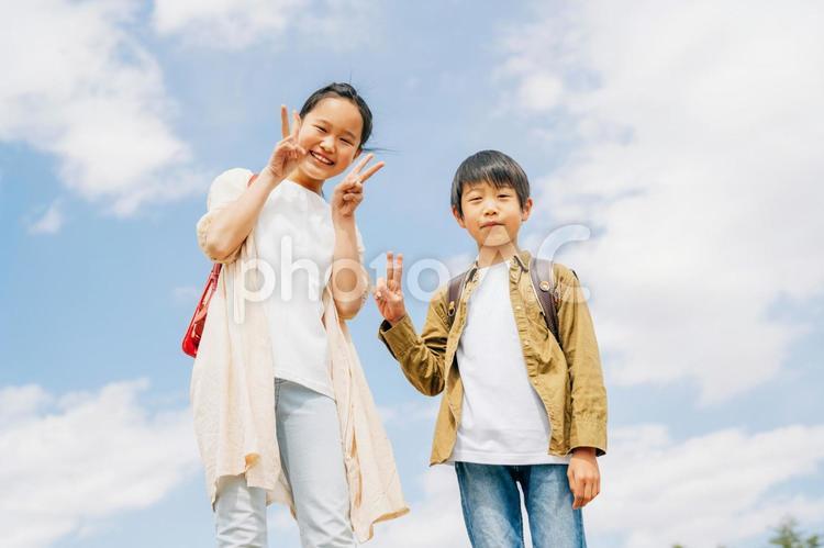 空と小学生（ピース） ピース,ポーズ,小学生の写真素材