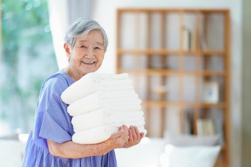 真っ白なタオルを持つ笑顔の高齢女性 女性,タオル,持つの写真素材